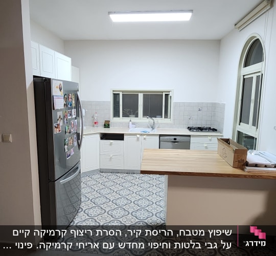 מטבח משופץ עם ארונות לבנים ודלפק עץ